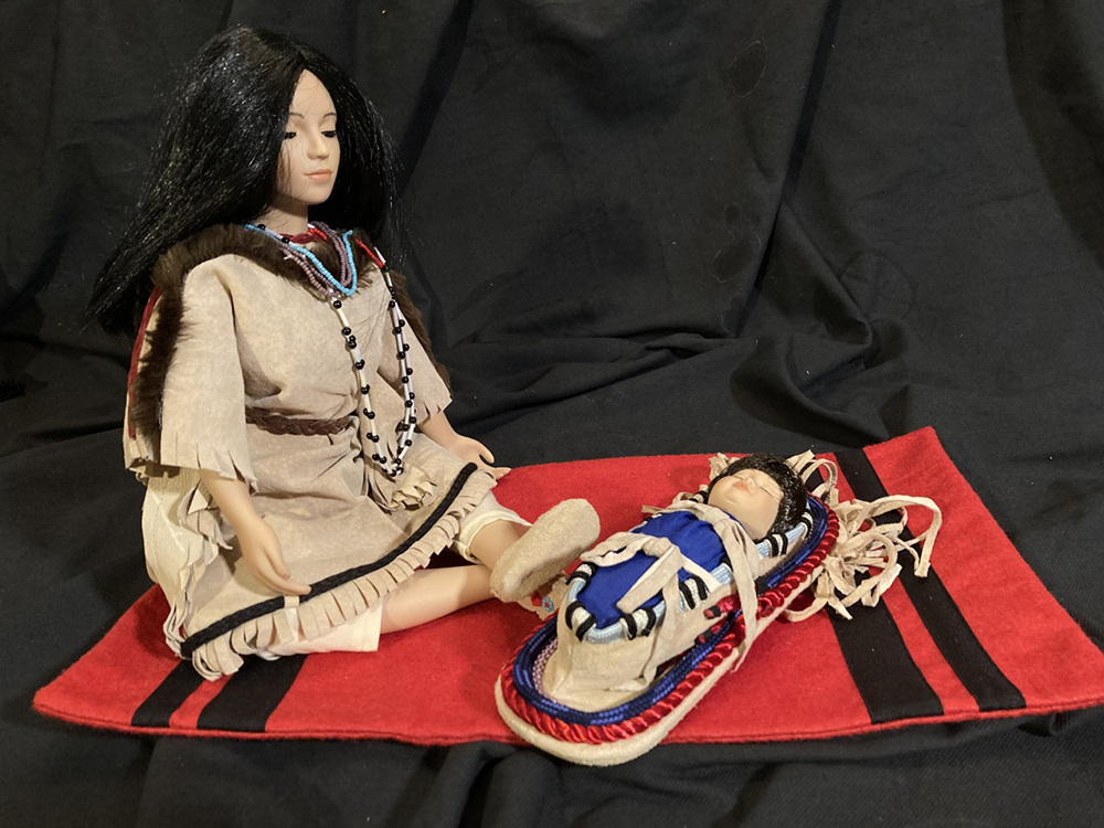 Collectible porcelain Pocohontas doll (18″) with a red blanket (16″ long) and a papoose in a fringed cradle (8″)